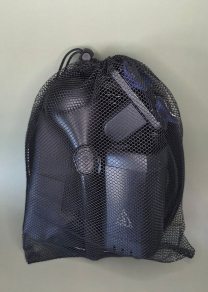 Black mesh bag containing the Avilo portable shower including all accessories with an olive background