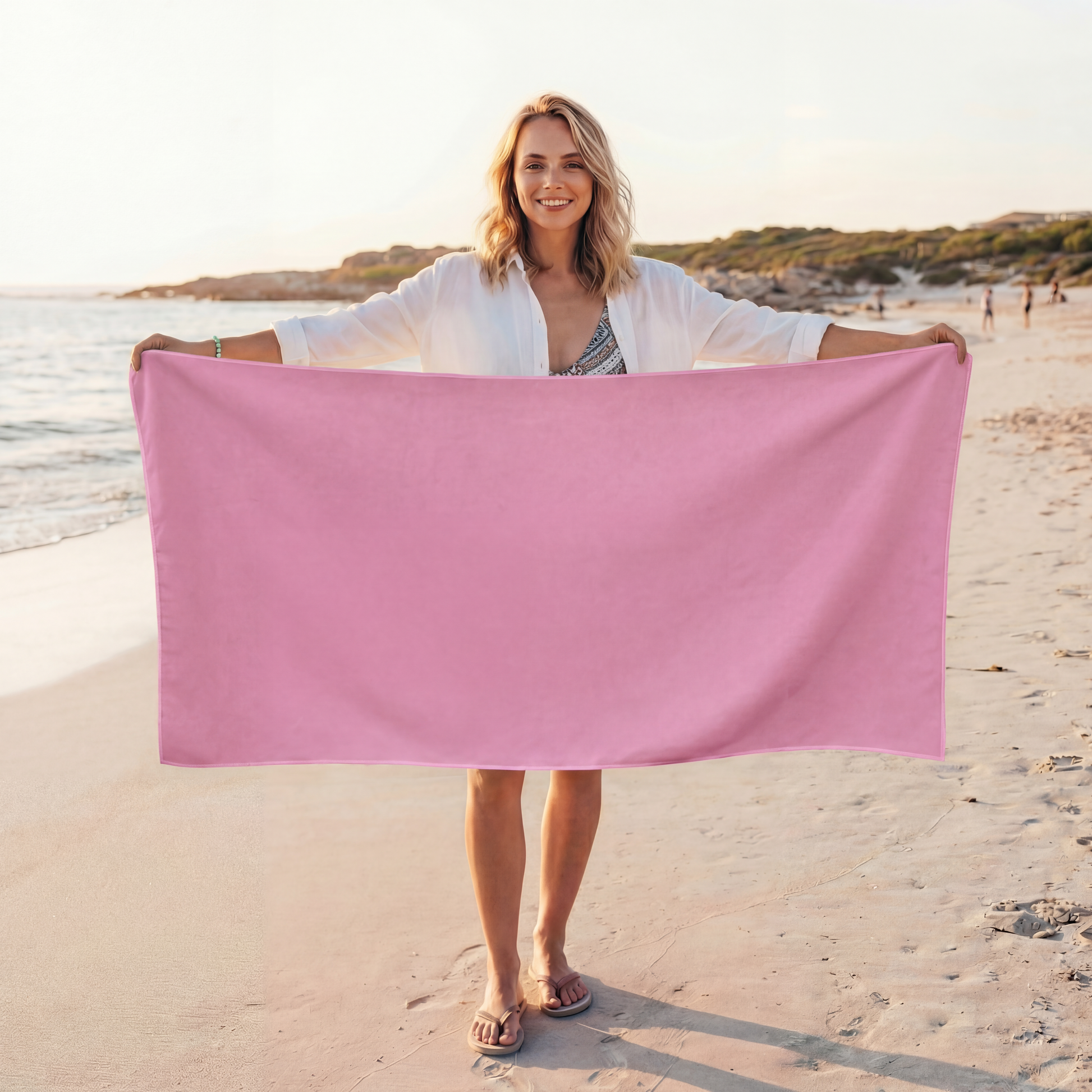 Woman holding a pink towel on a beach