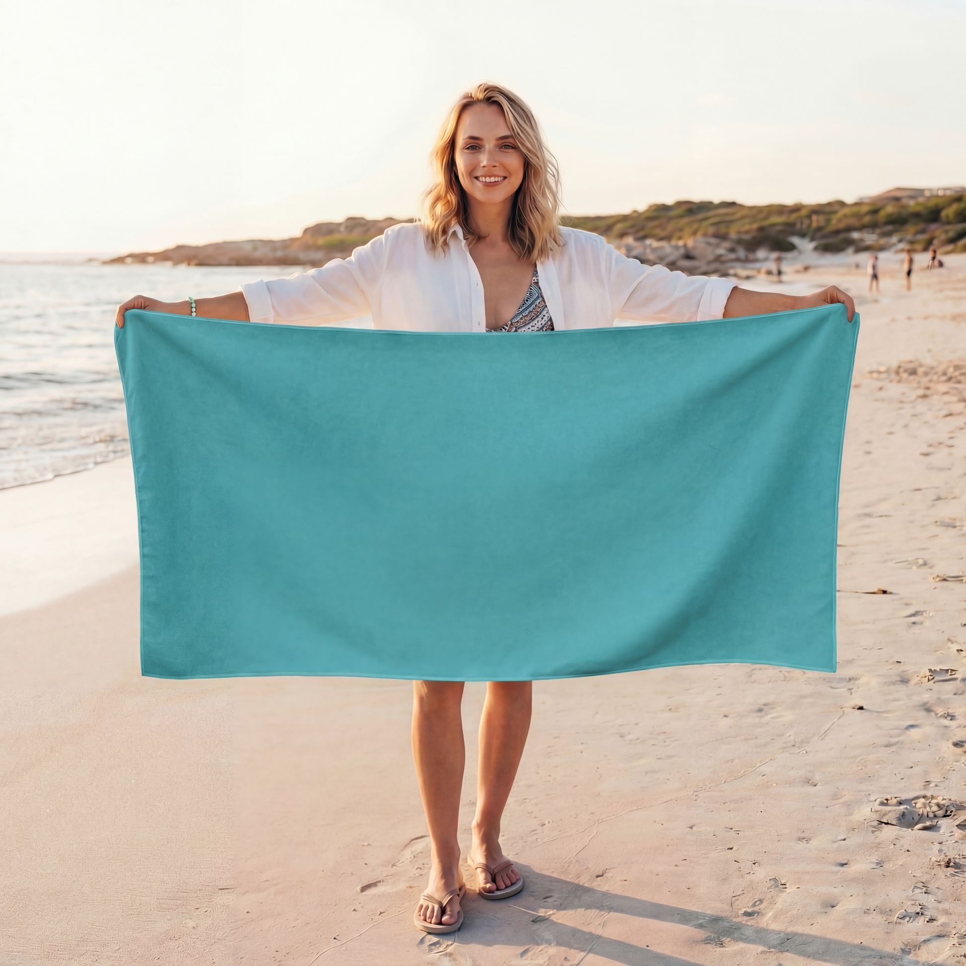 Woman holding a teal towel on a beach