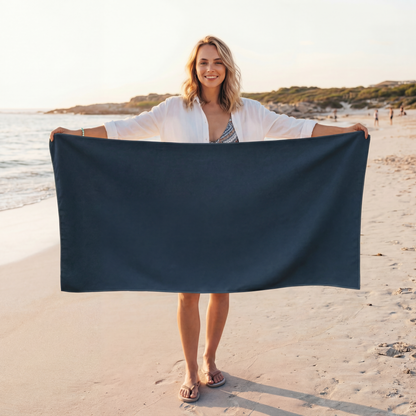 Woman holding a navy blue towel on a beach