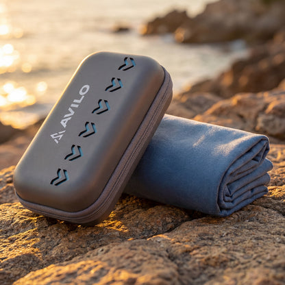 Folded towel and carrying case on a rocky beach with sunset