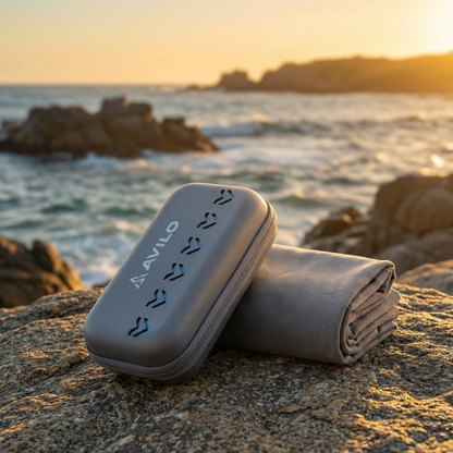 Folded Avilo microfibre towel and carry case on a rocky beach at sunset