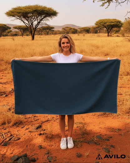 Person holding a blue towel in a savannah landscape with 'Avilo' branding.