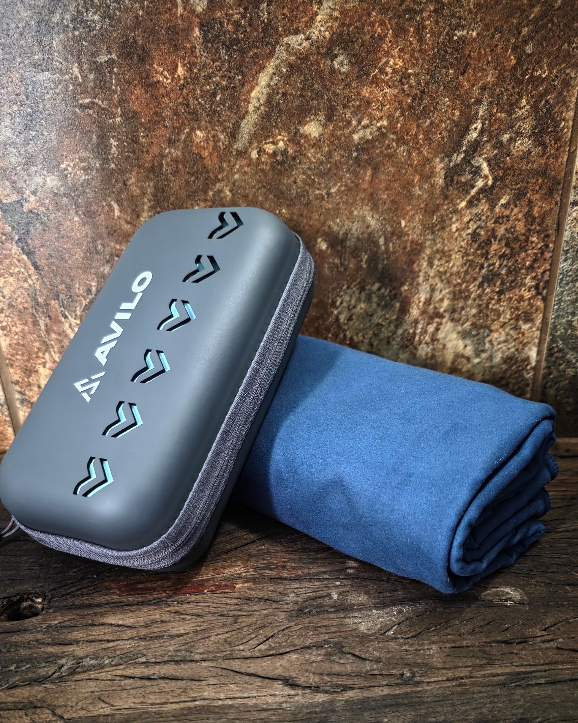 Blue towel and gray case with 'Avalon' branding on a wooden surface