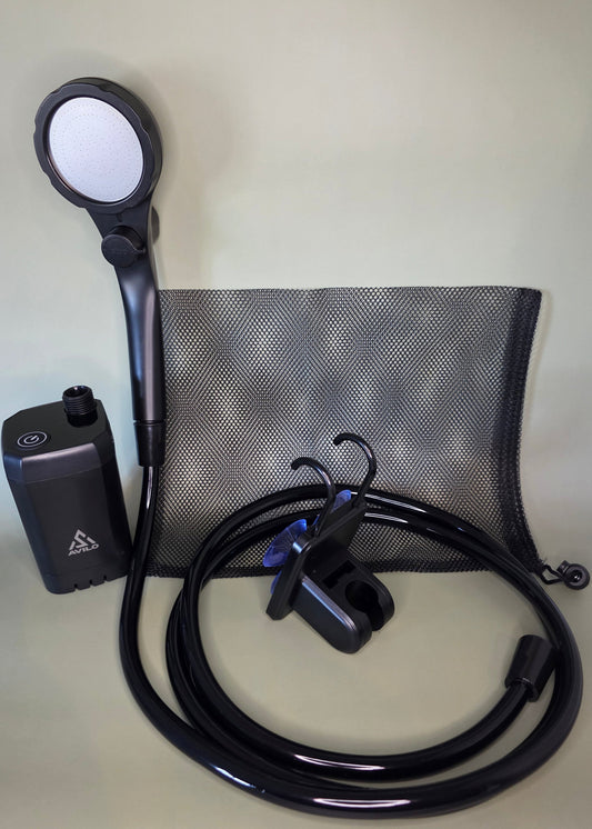 Black portable shower pump with hose, shower head and accessories on an olive background