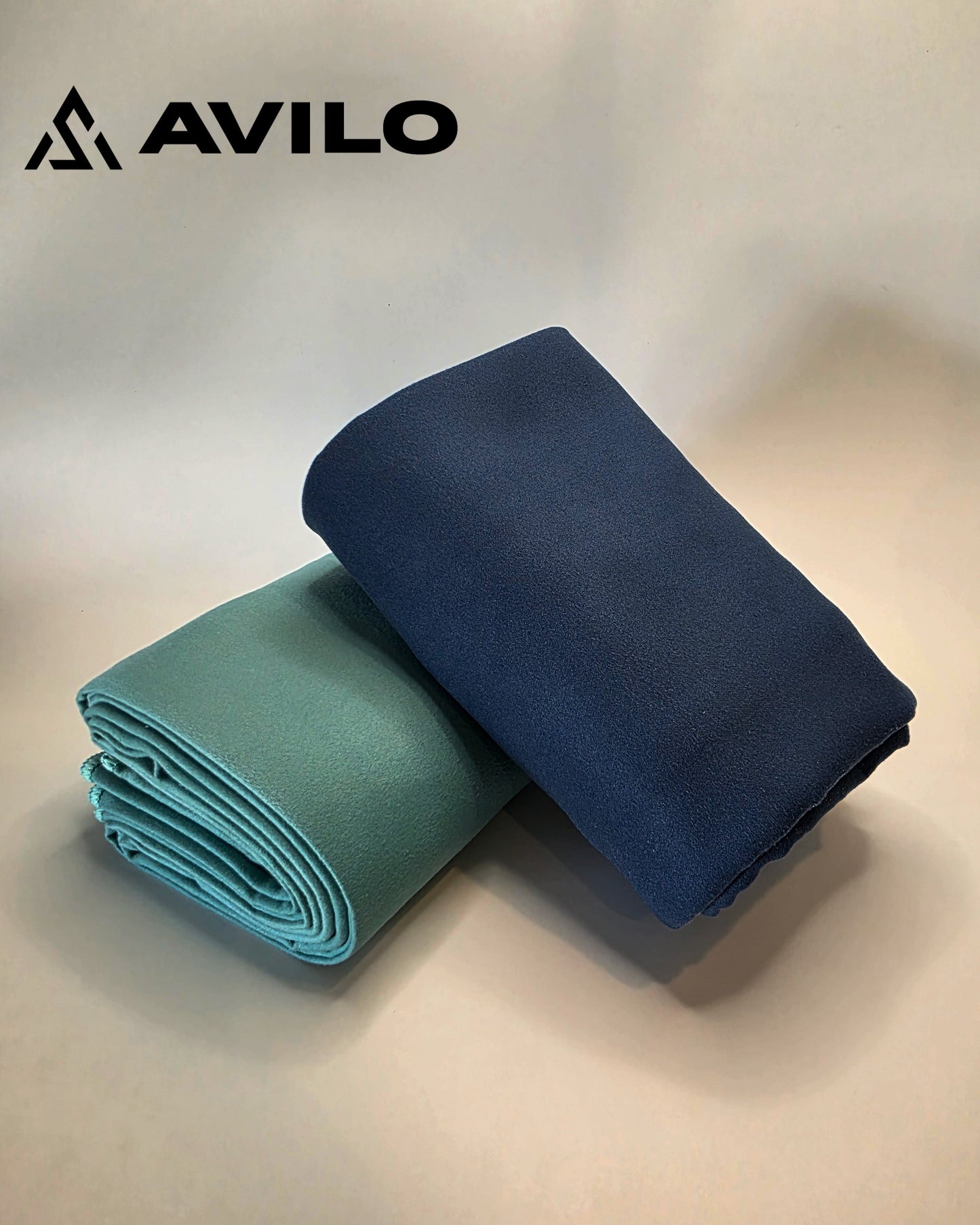 Two folded towels, one blue and one green, on a light background with Avilo logo.