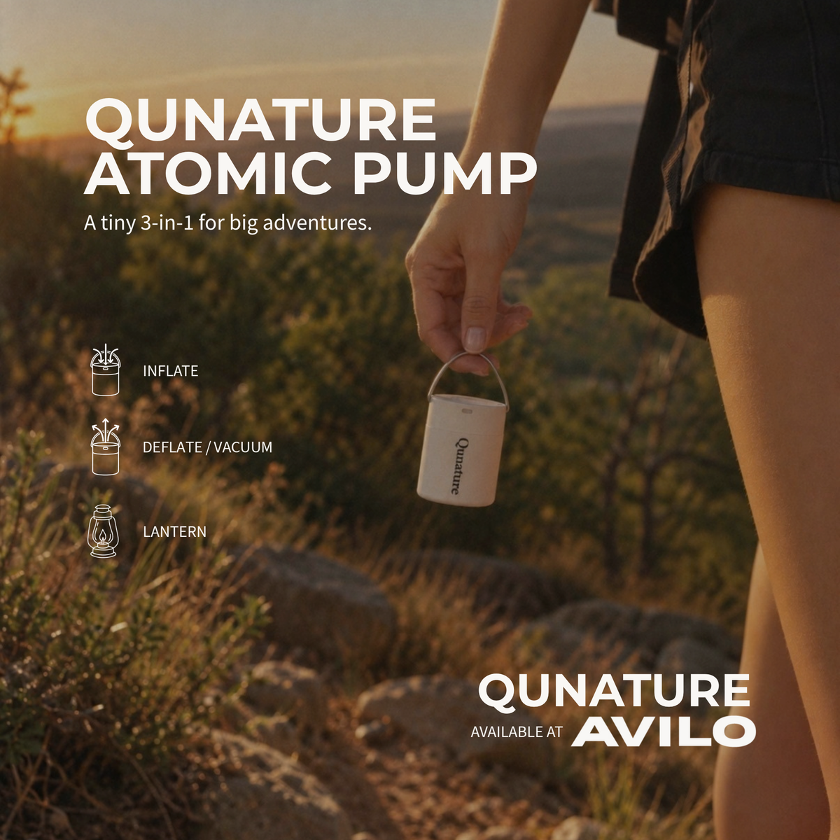 A hand carries the white Qunature Atomic Pump by its loop on a hillside at sunset. It inflates, deflates or vacuums, and doubles as a lantern