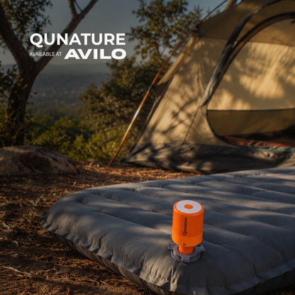 The orange pump fitted into the valve of an air mattress outside a tent