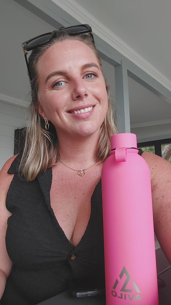 A customer on a covered stoep talks to camera about her bright pink Avilo flask.