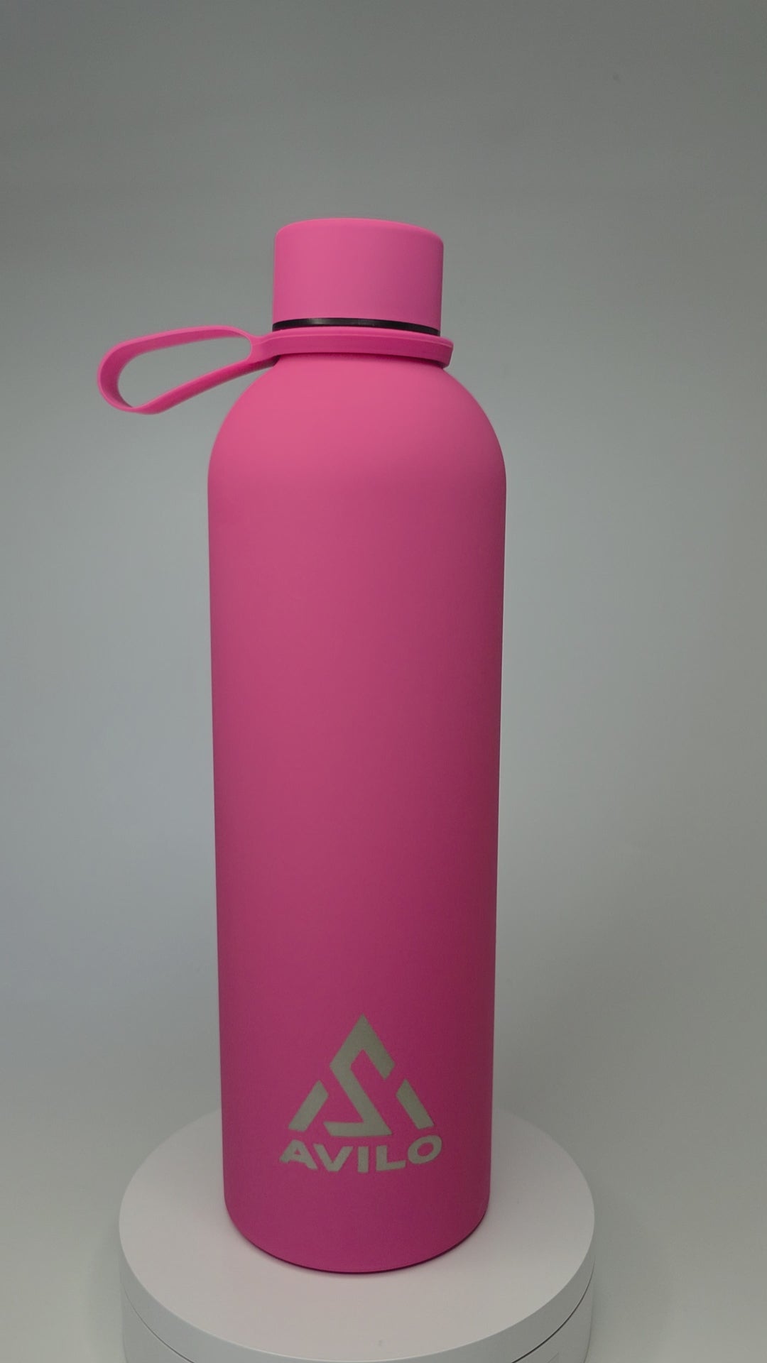 A pink Avilo insulated flask turning slowly on a white pedestal against a studio backdrop.